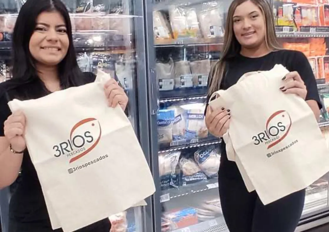 Duas promotoras com ecobags da marca em frente ao freezer